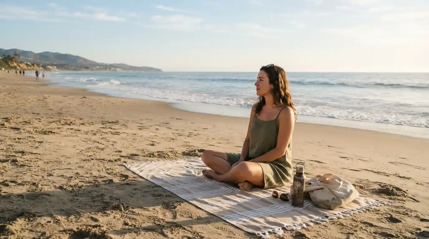 Person relaxing on a beach towel beside the ocean during a peaceful afternoon